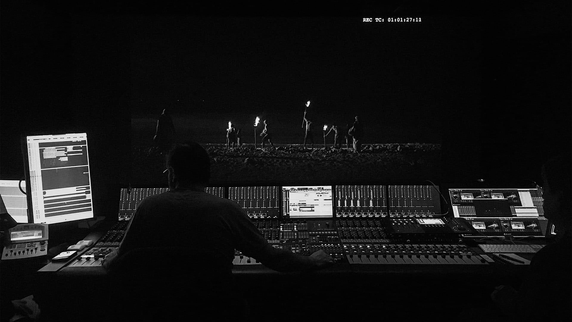 Sound designer at a mixing desk in a dark studio