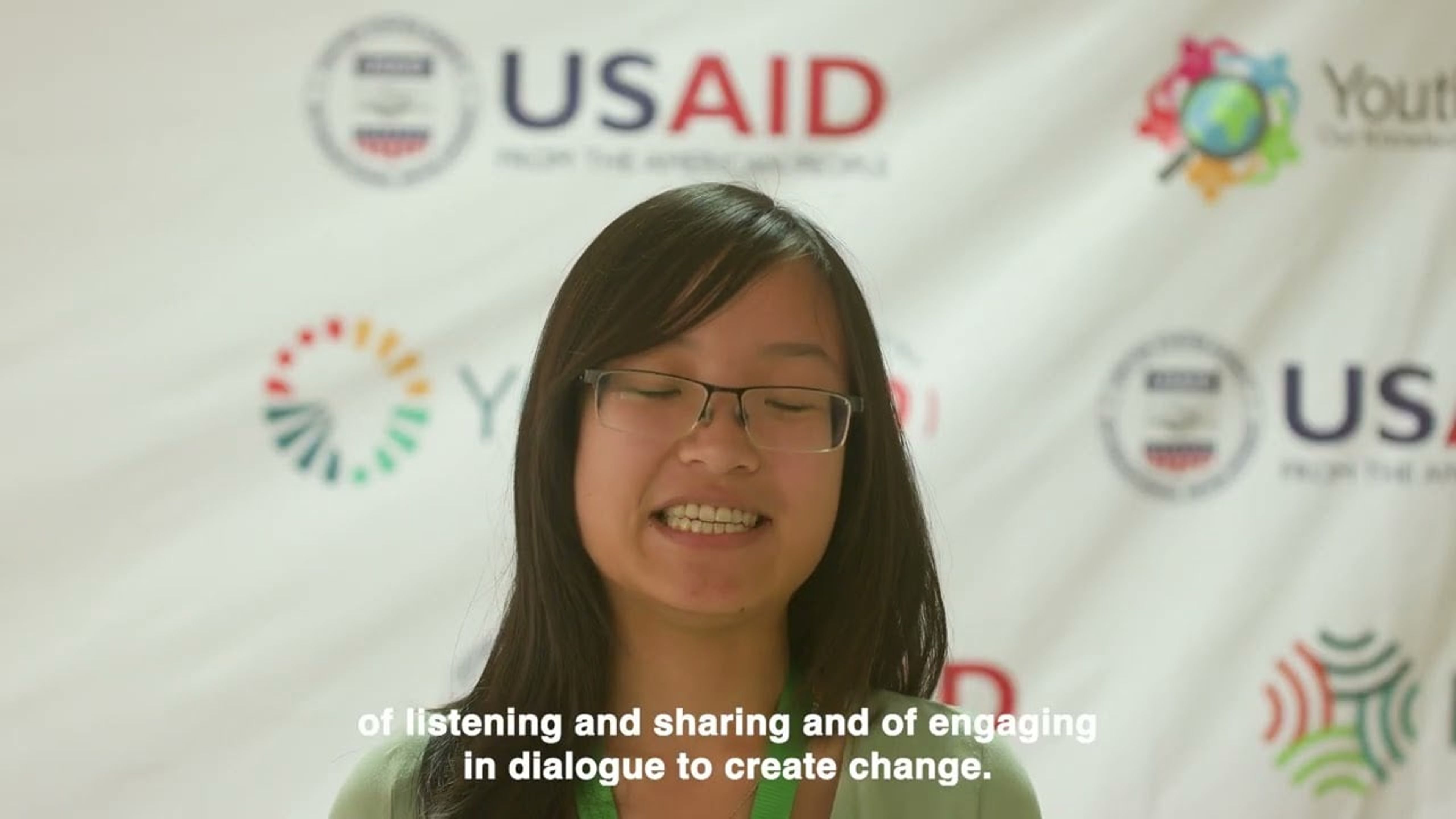 A speaker at the Youth Drive Change Summit in front of a USAID banner