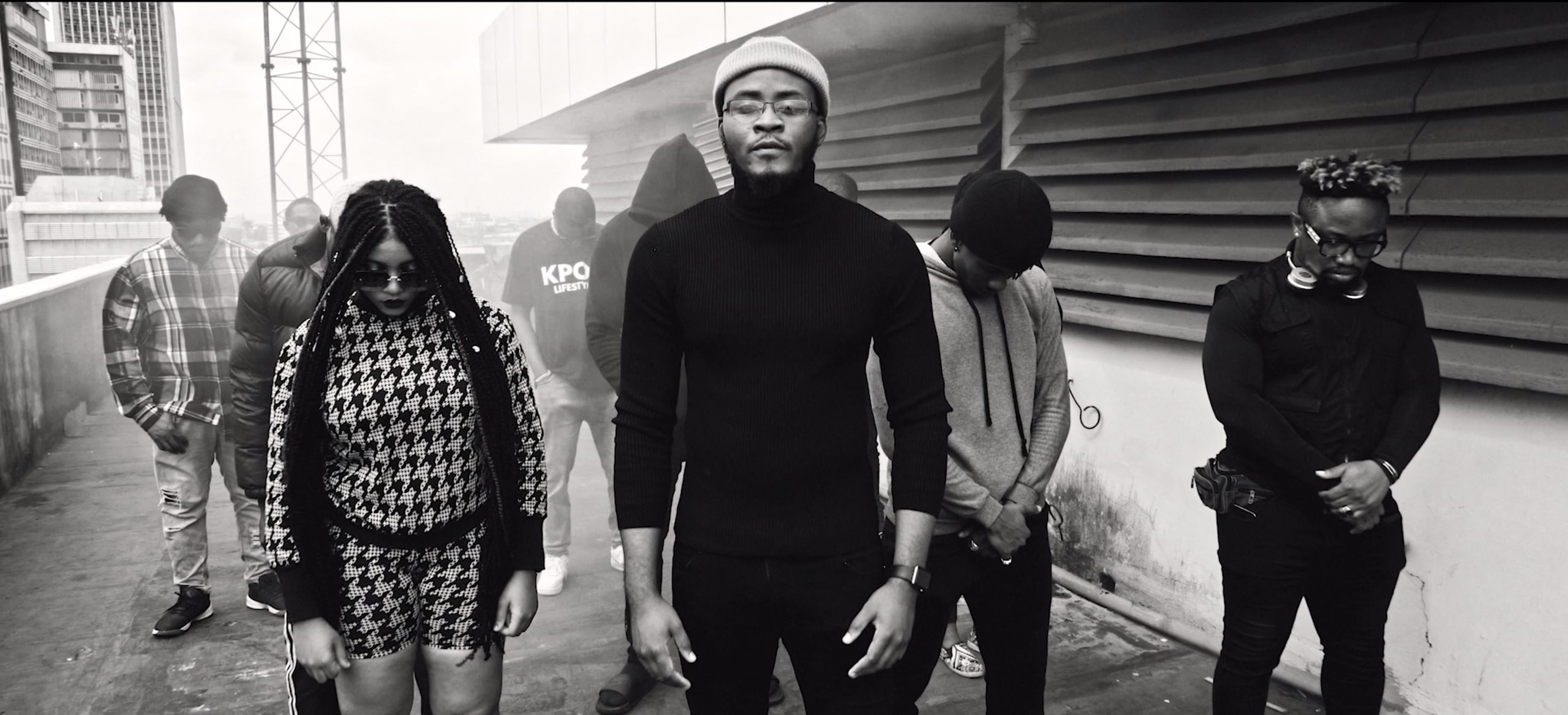 Black-and-white shot of a group of young people standing along a street wall