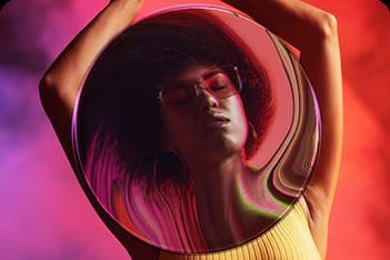 Portrait of a woman seen through a glass sphere in pink and red light