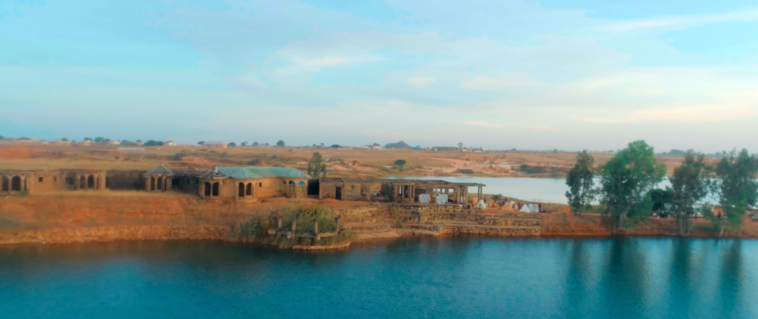 A still lake at dusk with low hills on the horizon