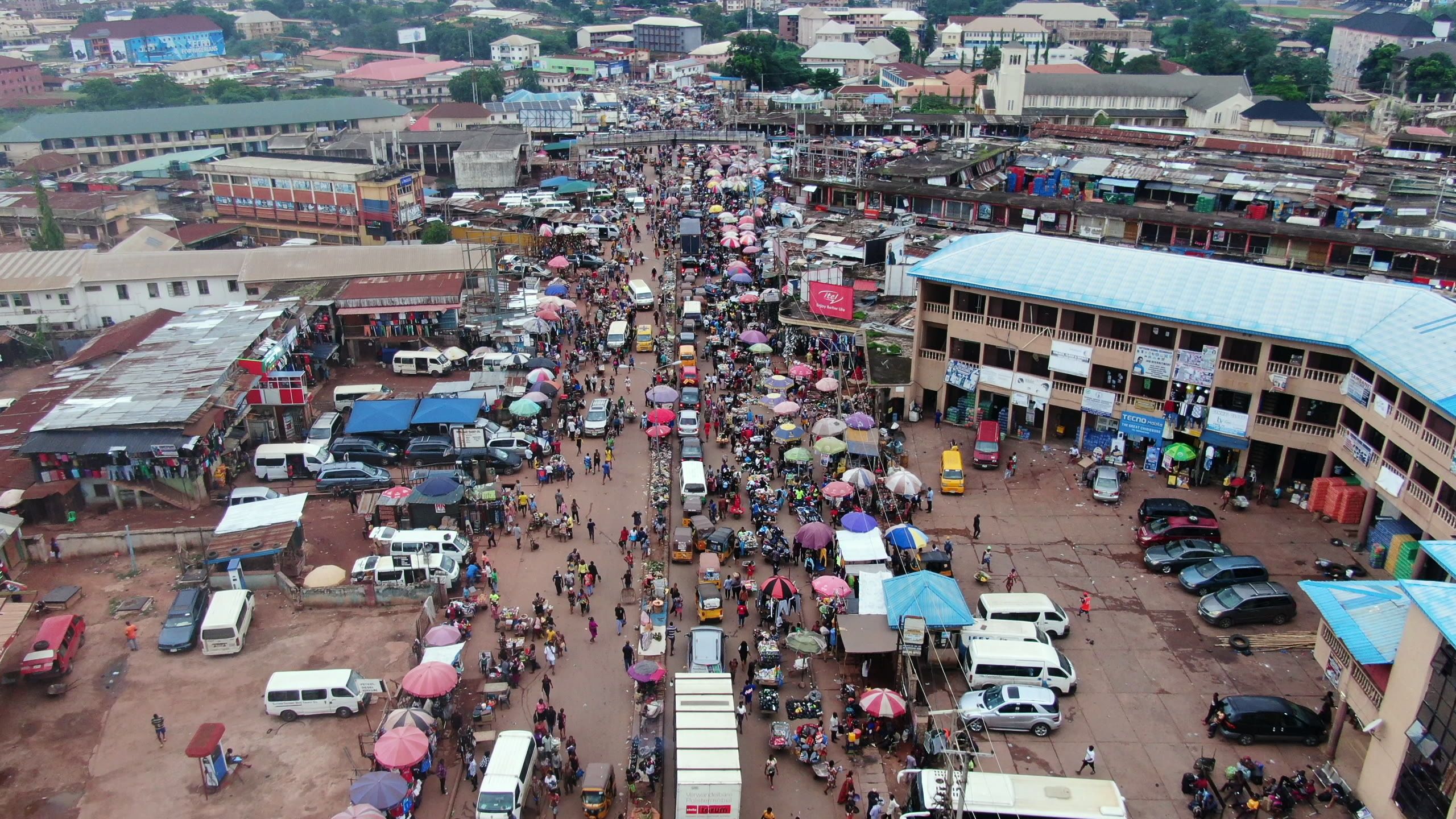 Aerial view of a crowded market with colourful umbrellas and red rooftops