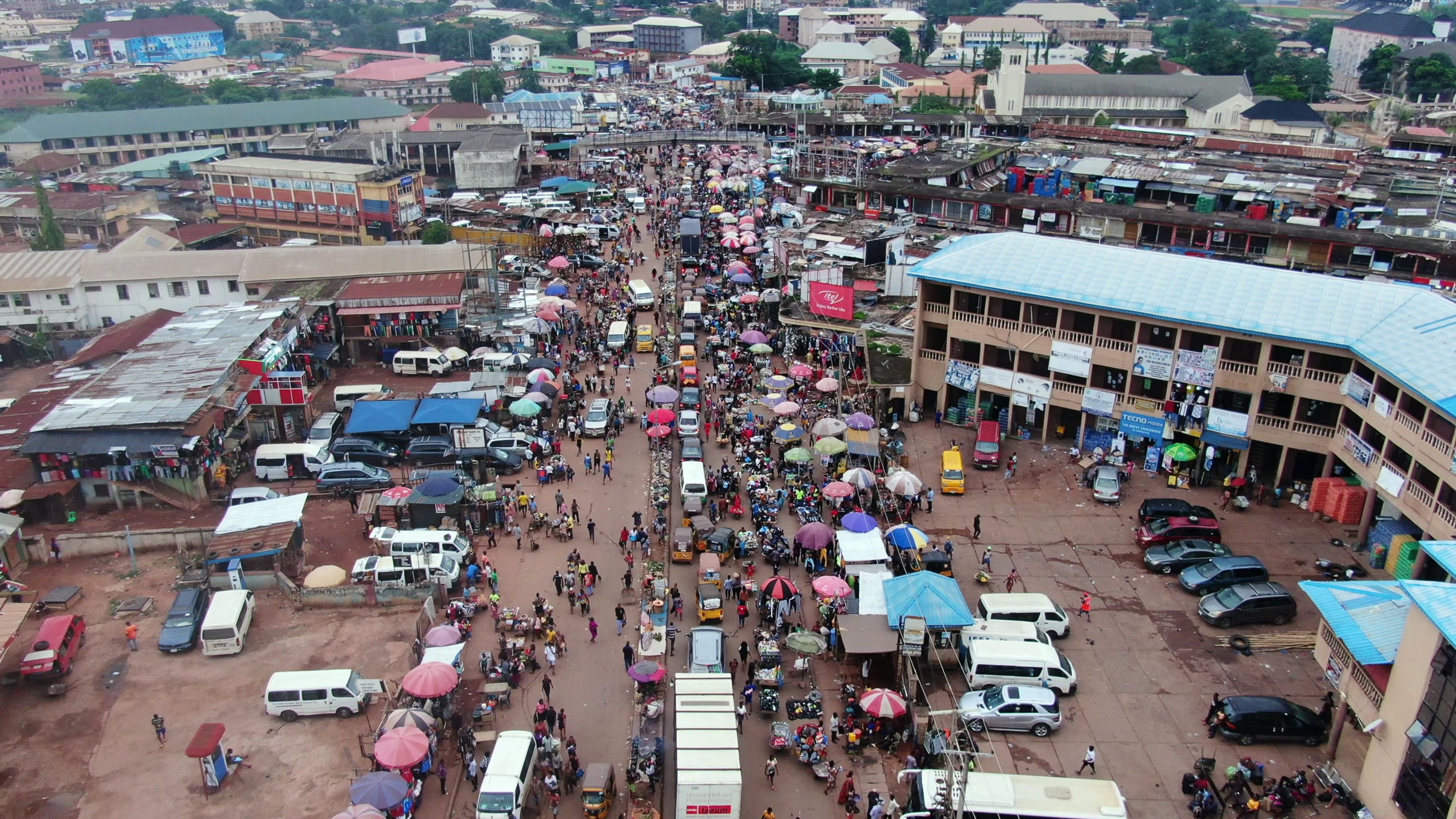Aerial view of a crowded market with colourful umbrellas and red rooftops