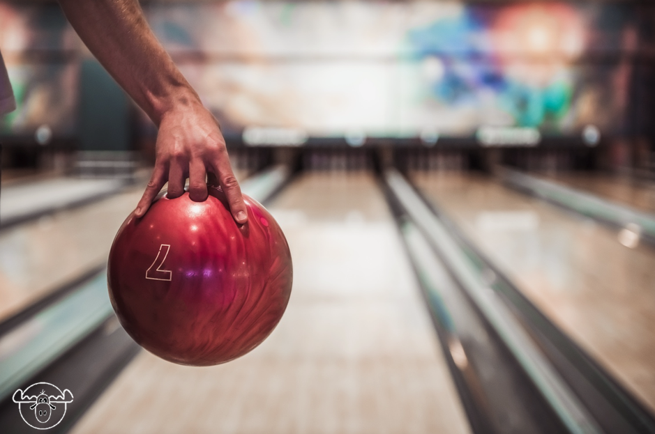 A bowler releasing the ball down a neon-lit lane