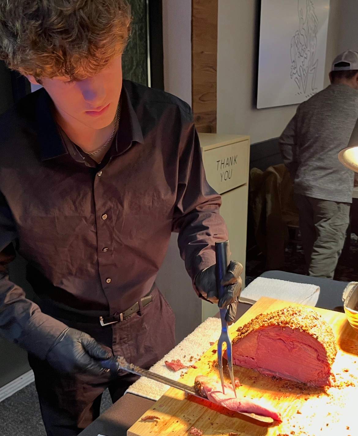 A Bullwinkle's staff member carving prime rib under a heat lamp