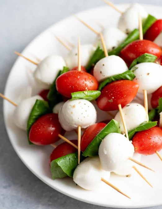 Caprese skewers of cherry tomato, basil and mozzarella on a plate