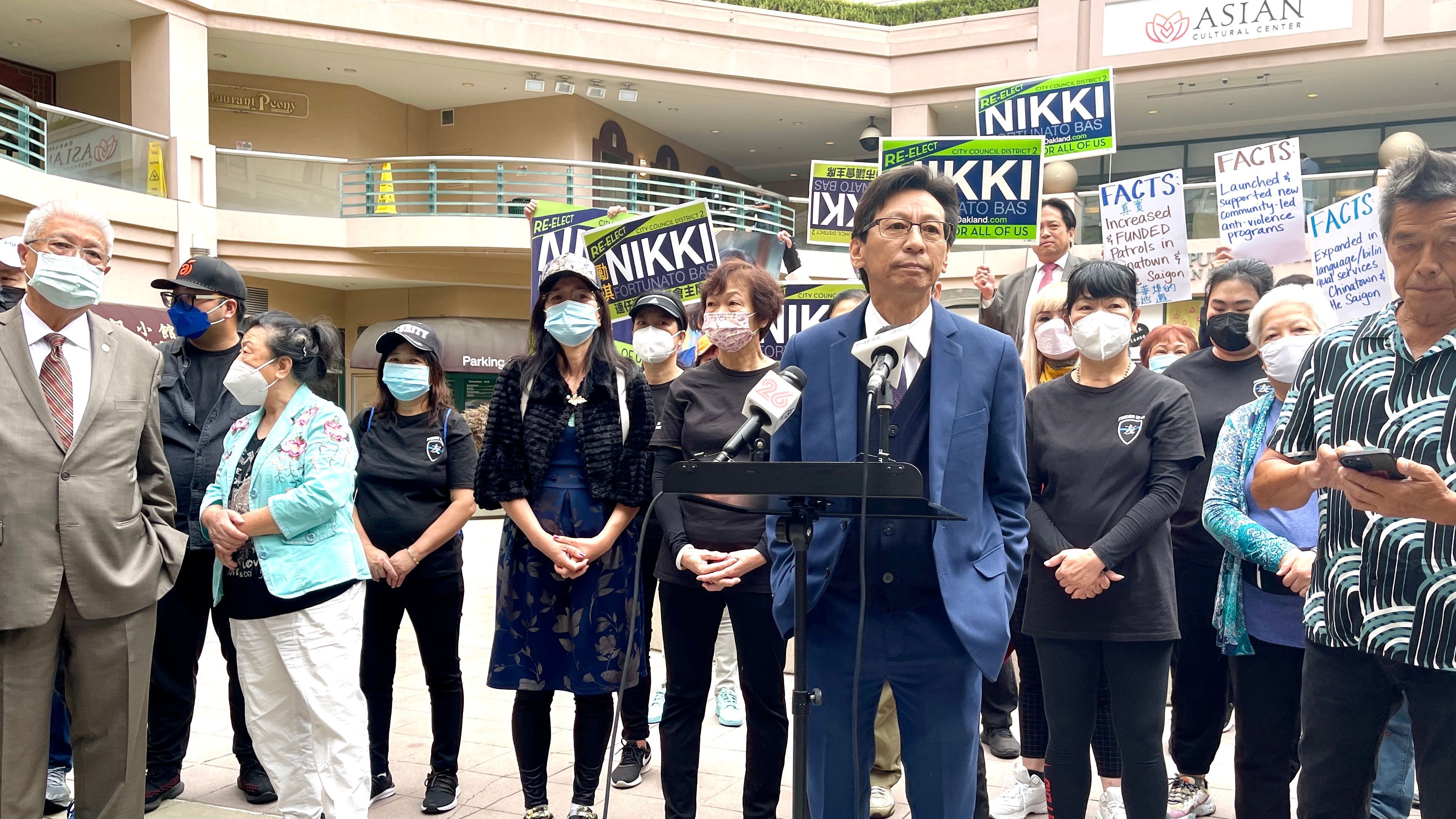 Carl Chan (center) and Oakland Chinatown leaders host a press conference to call for City Council President Nikki Fortunato Bas to resign. Bas’ supporters hold signs standing behind. Photo by Portia Li