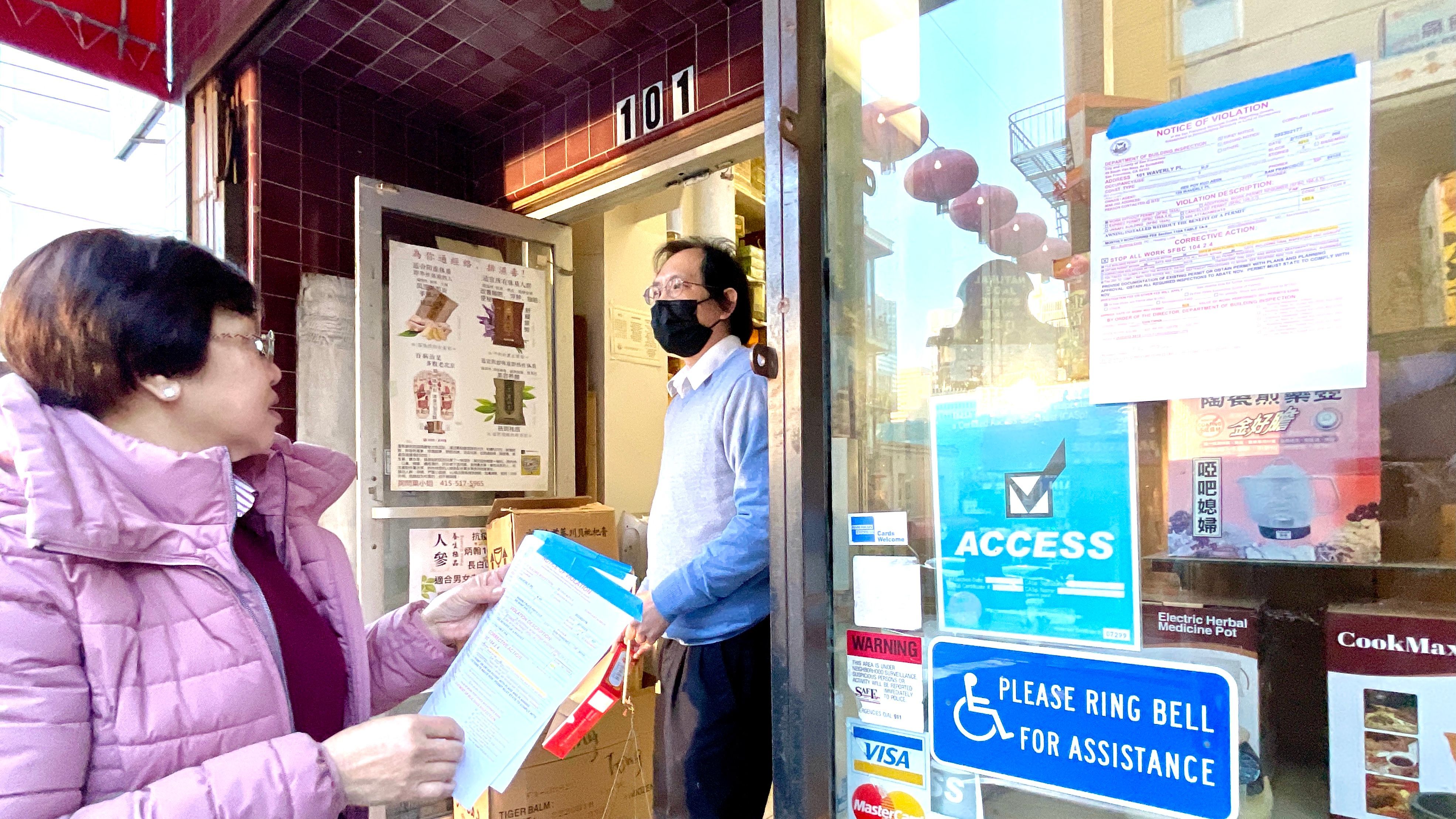 Northeast Community Credit Union CEO Lily Lo (left) offers assistance to several dozen business and property owners who receive notices of violations on awnings and security gates. Photo by Portia Li