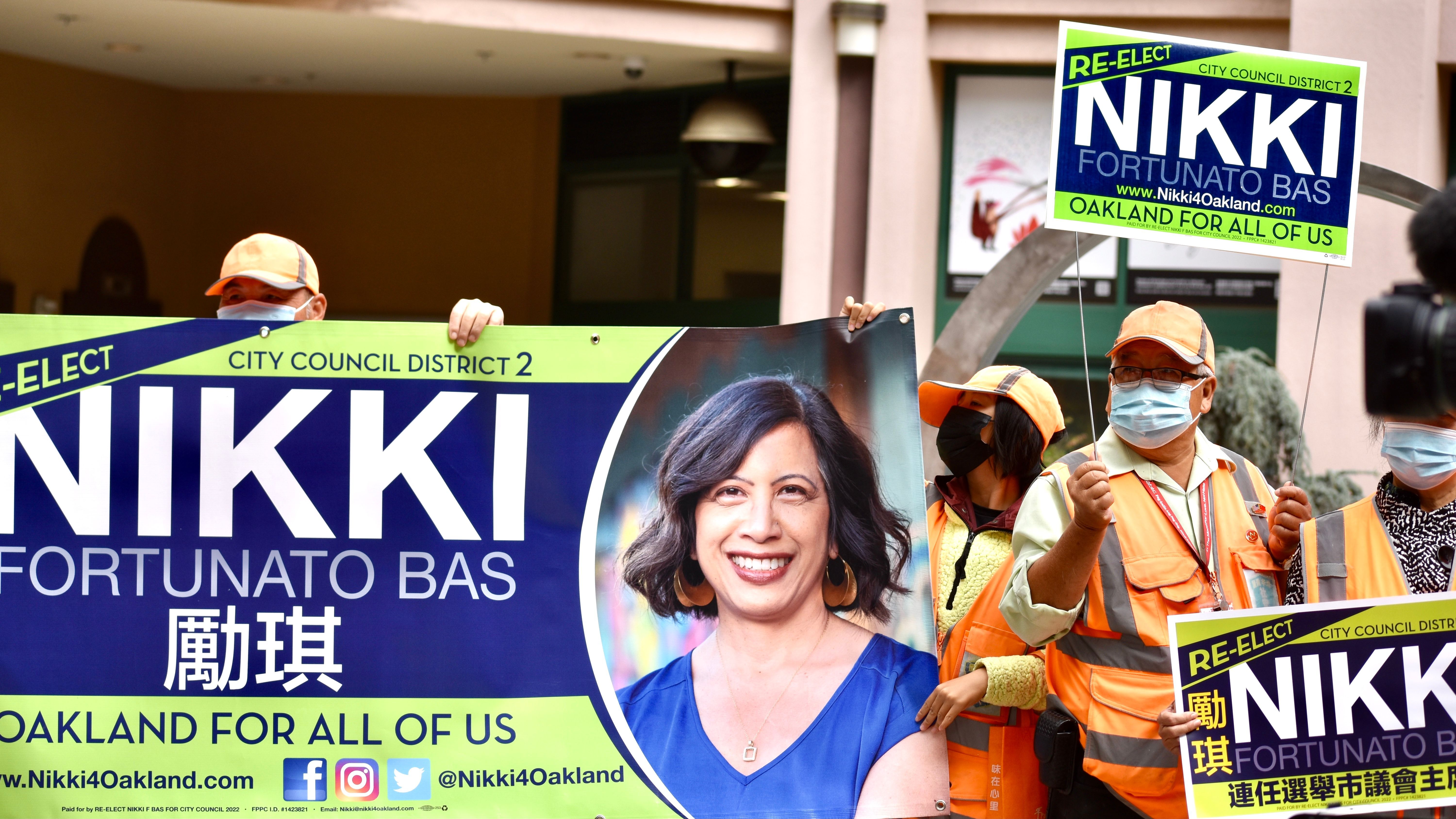 Supporters of Oakland City Council President Nikki Fortunato Bas’hold a large sign of her re-election campaign to defend her record on public safety. Photo by Portia Li