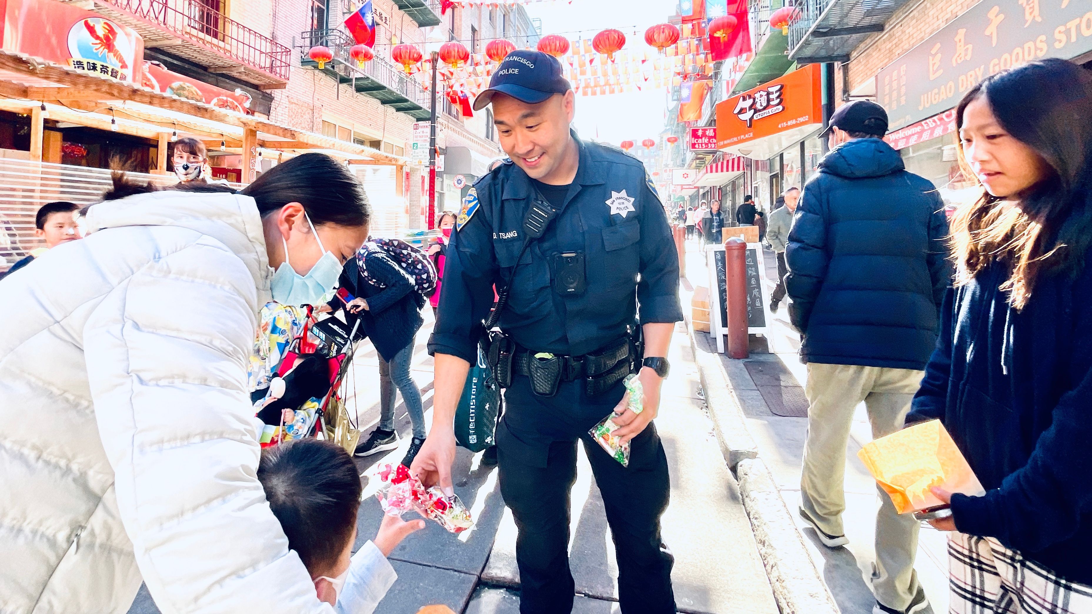 Chinatown beat officer Dexter Tsang distributes holiday goody bags to children on Waverly Place. Photo by Portia Li