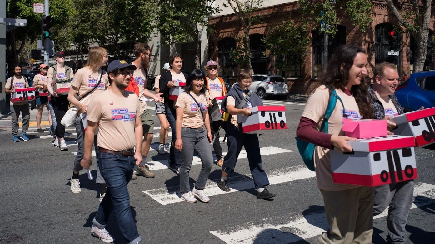 Transit advocates carry boxes of signatures walking to City Hall to submit their petition for placing a ballot measure to fund Muni bus services. Courtesy Ben Cochran