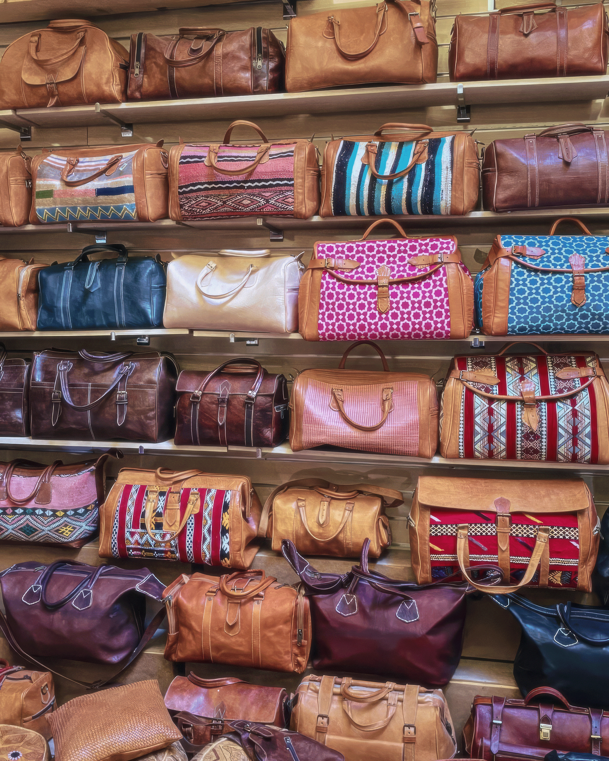Collection de sacs en cuir artisanaux et duffel bags en kilim exposés sur des étagères