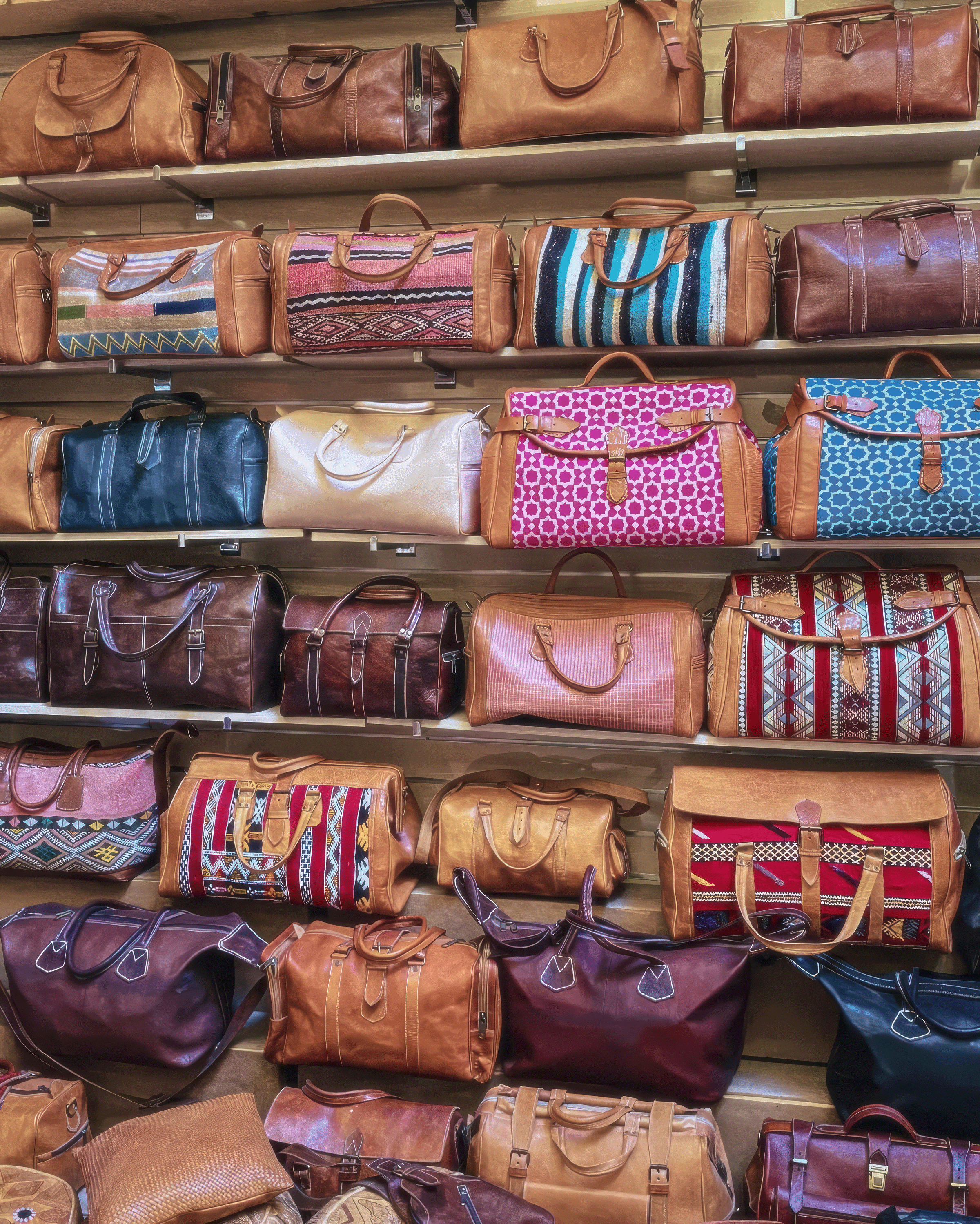 Collection de sacs en cuir artisanaux et duffel bags en kilim exposés sur des étagères