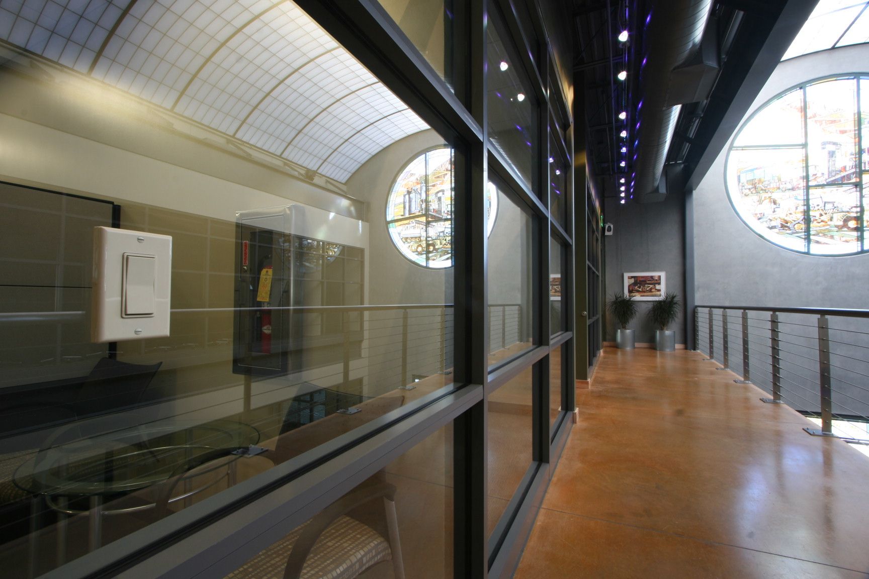 Modern hallway with a glass partition with a wireless light switch mounted on glass, round cityscape windows, and an arched ceiling