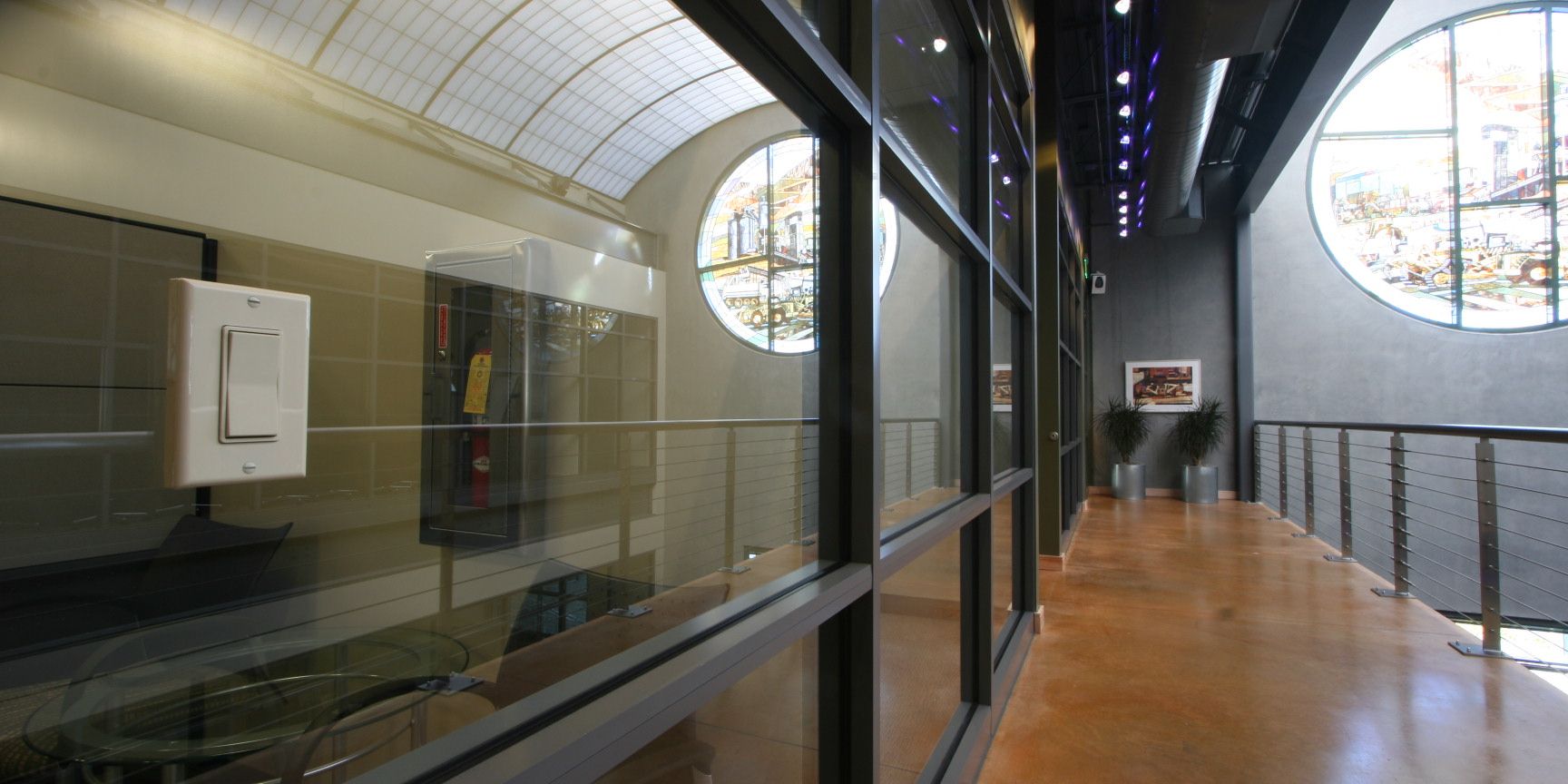 Modern hallway with a glass partition with a wireless light switch mounted on glass, round cityscape windows, and an arched ceiling