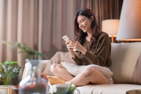 Mulher curtindo celular no sofá