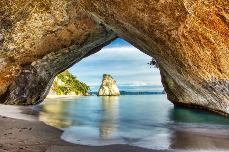 The rock arch at Cathedral Cove framing the beach and a rock stack in the sea