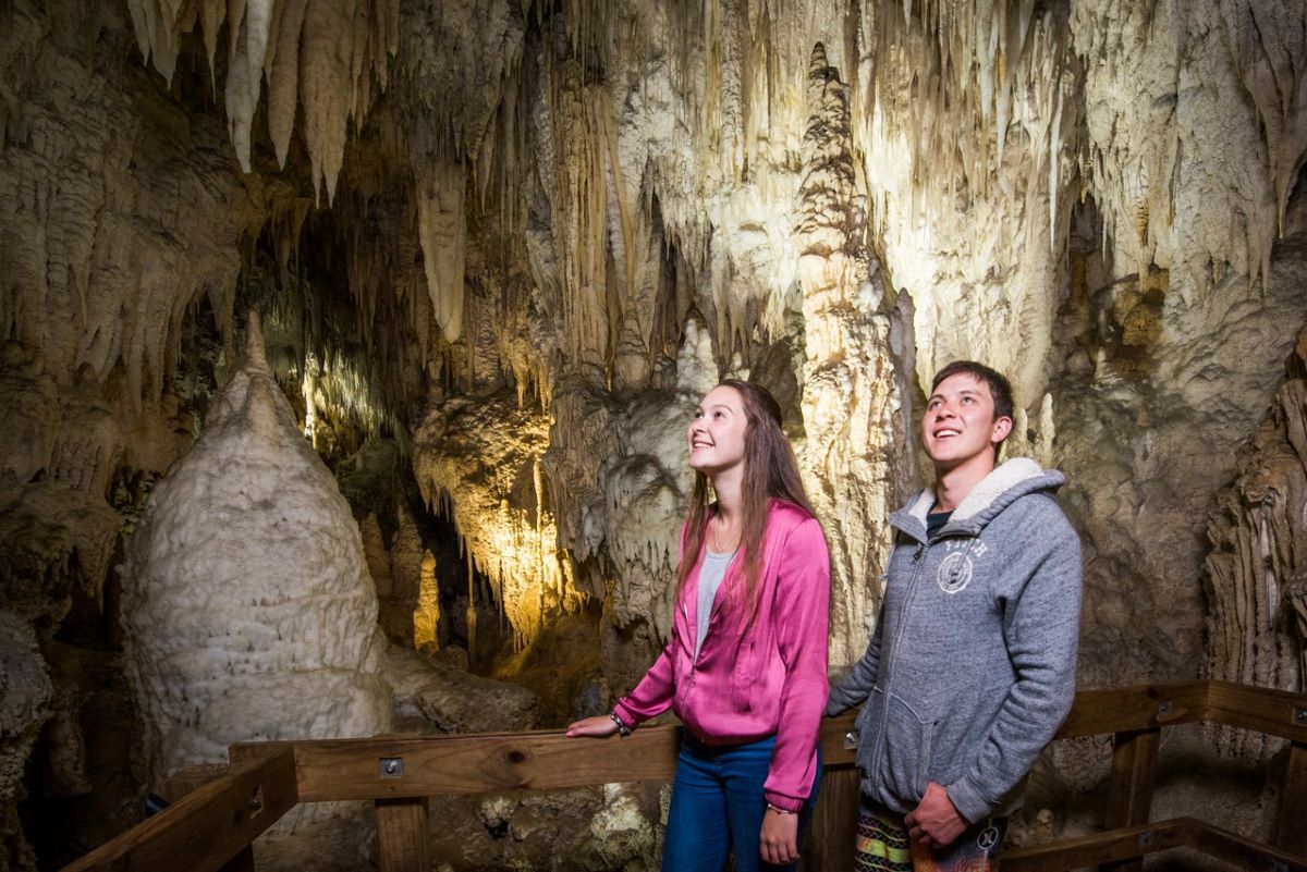 A couple exploring the limestone formations of Aranui Cave, Waitomo