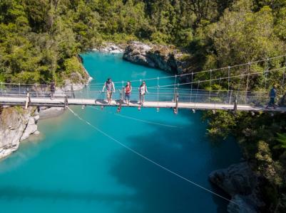 Travellers on the swing bridge over the turquoise waters of Hokitika Gorge