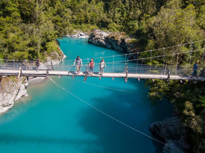 Travellers on the swing bridge over the turquoise waters of Hokitika Gorge