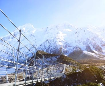 A swing bridge on the Hooker Valley Track beneath the snow-capped Southern Alps
