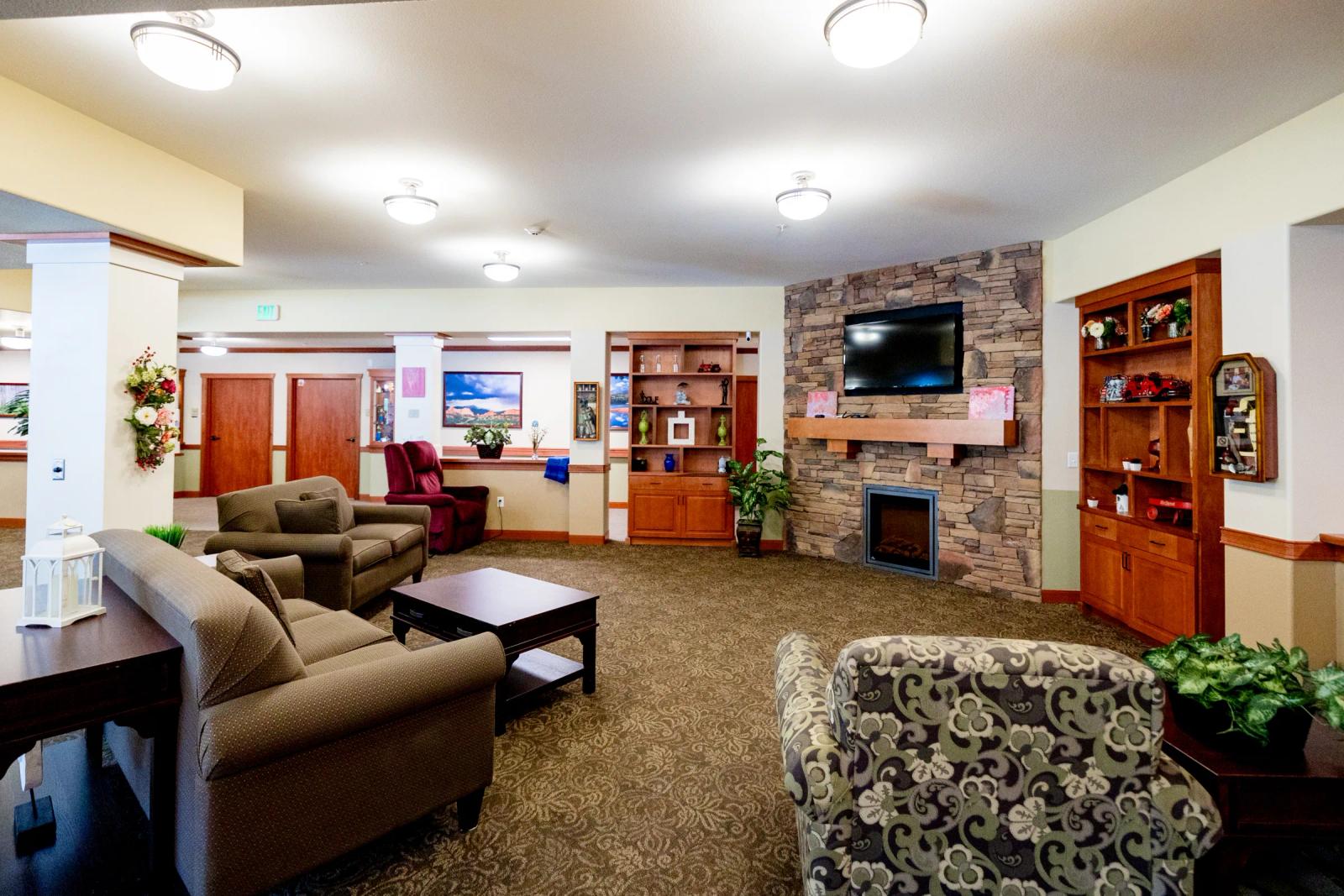 Gardens on Quail memory care lounge with sofa, fireplace, and display cabinets