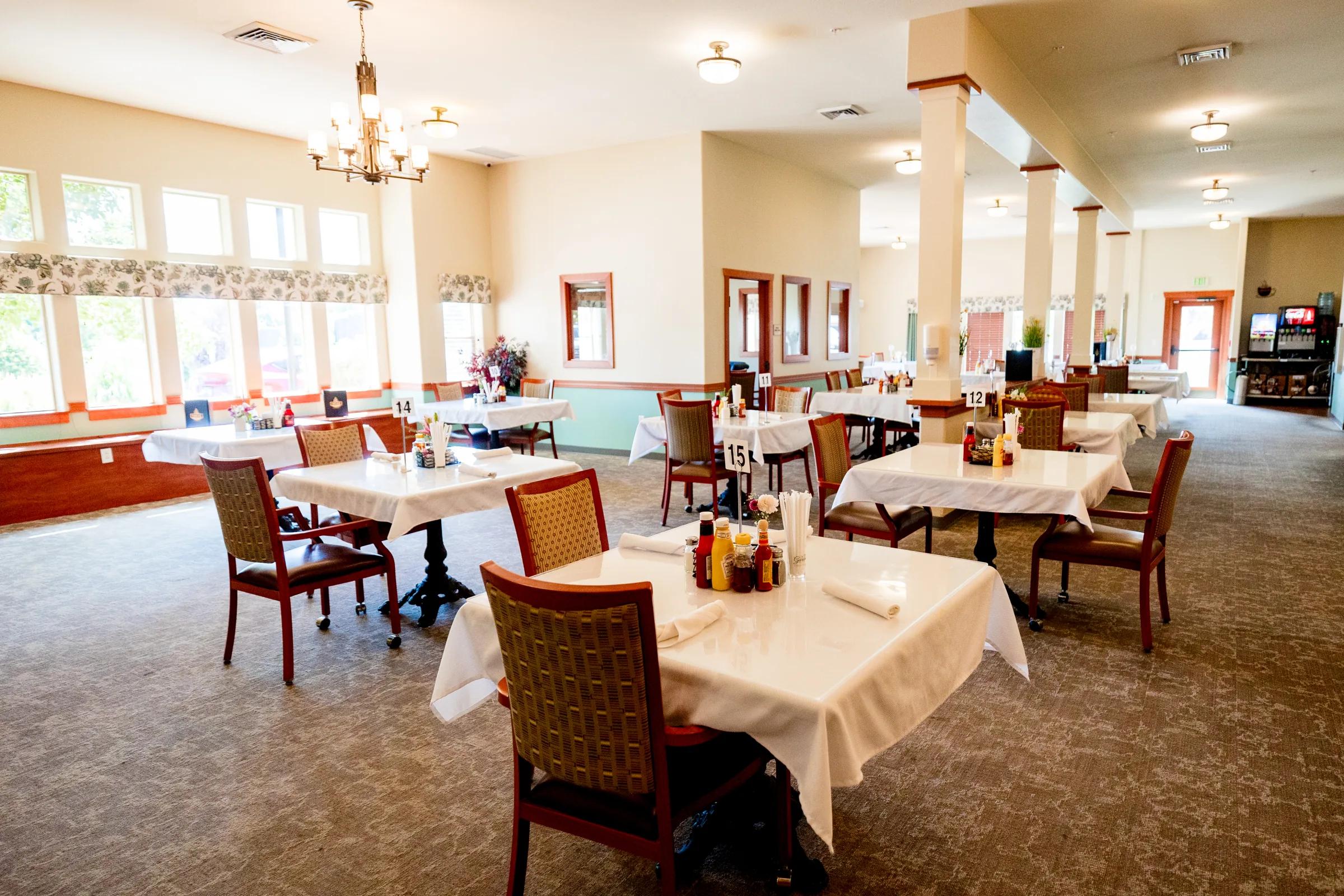 Gardens on Quail main dining room with set tables, columns, and chandelier