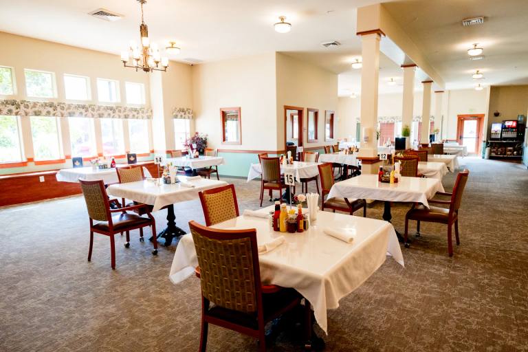 Gardens on Quail main dining room with set tables, columns, and chandelier