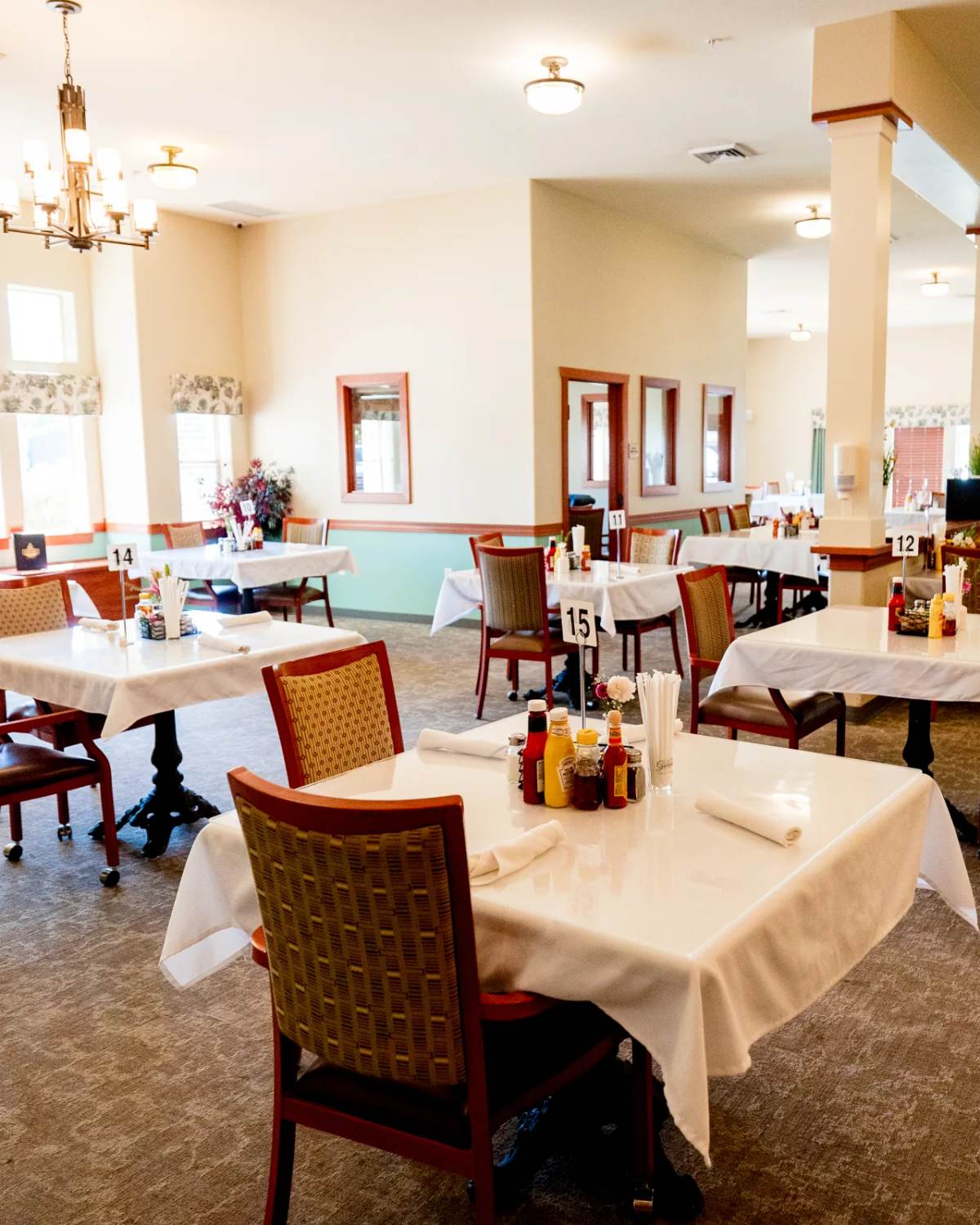 Gardens on Quail main dining room with set tables, columns, and chandelier