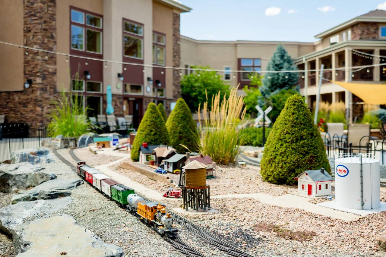 Gardens on Quail model train garden with miniature depot buildings and train on tracks