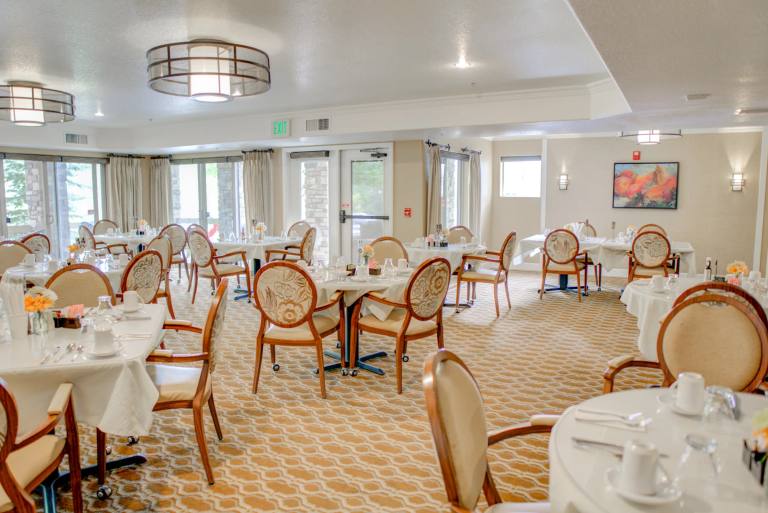 Golden Pond main dining room with round tables, upholstered chairs, and arched walls