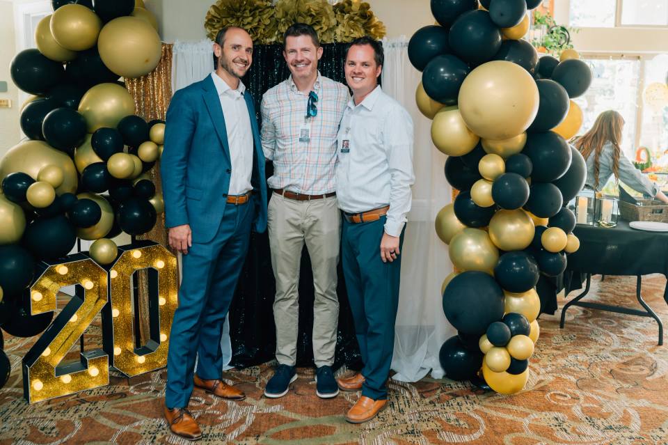 Three Golden Pond staff members posing in front of the 20-year gala balloon arch.