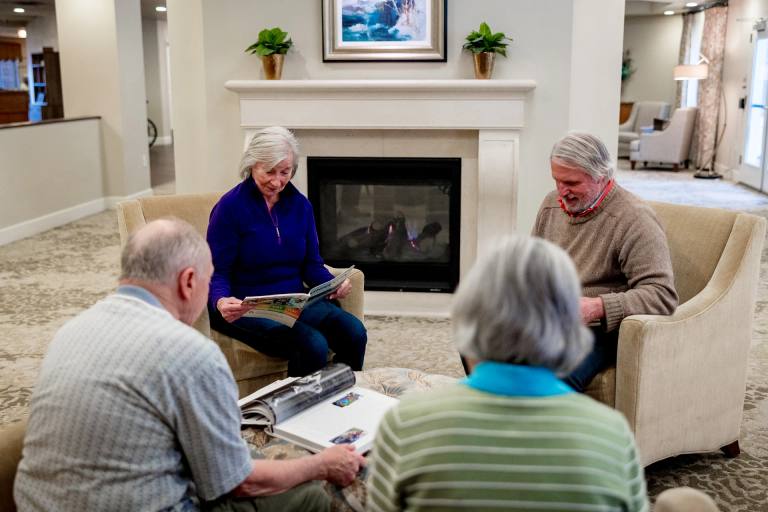 Stonebridge Senior residents look through photo albums together by the fireplace