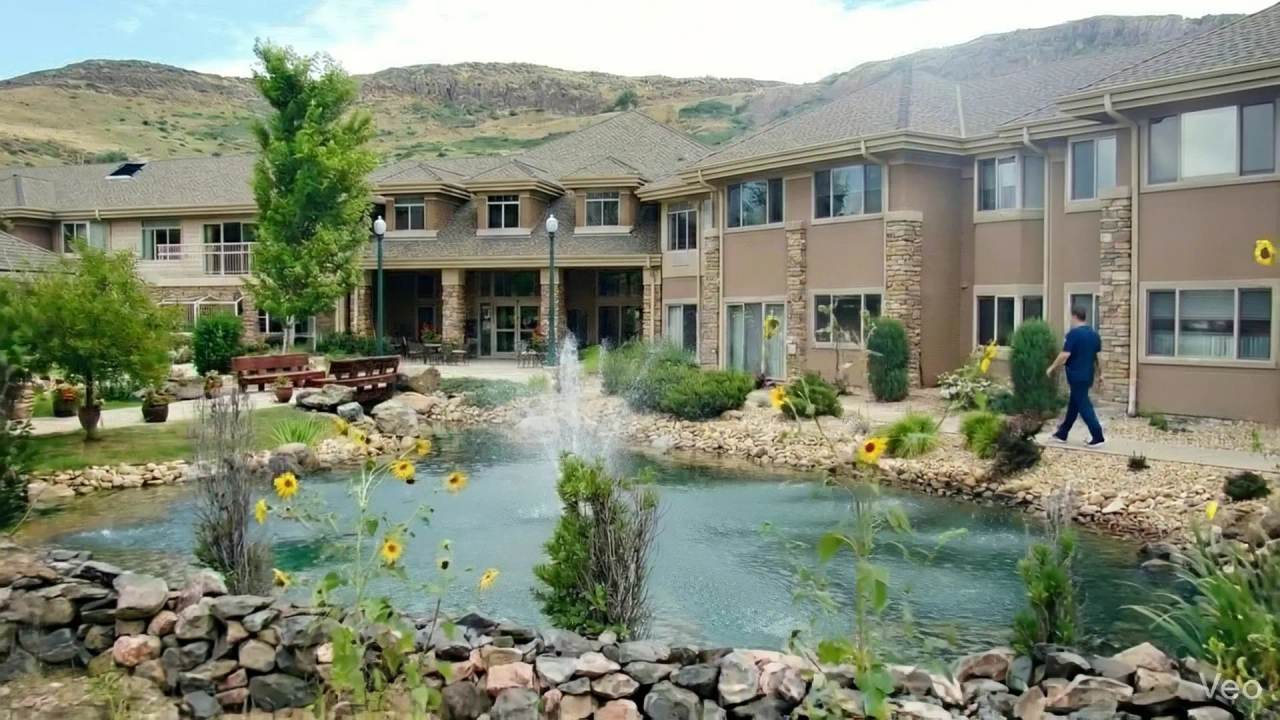 Golden Pond courtyard with a pond fountain, garden seating, and foothills behind the community
