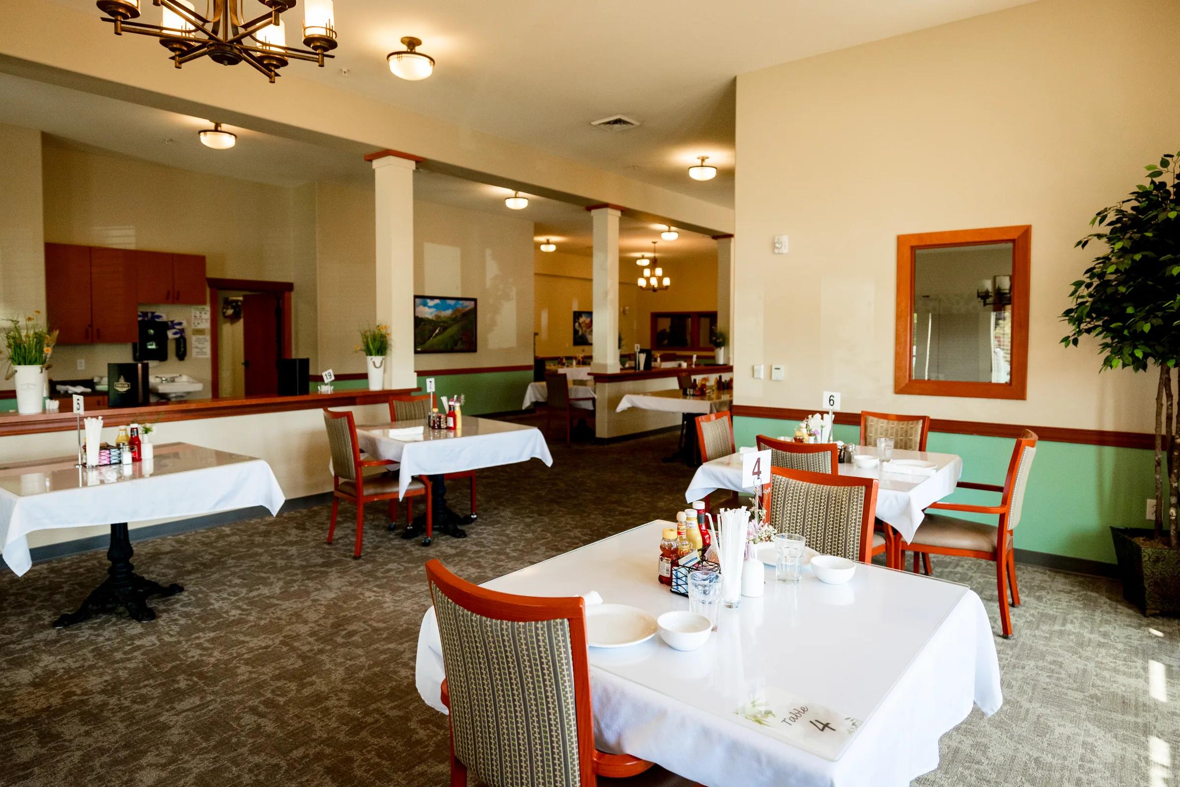 Gardens on Quail bistro dining with orange chairs, white tables, and framed art