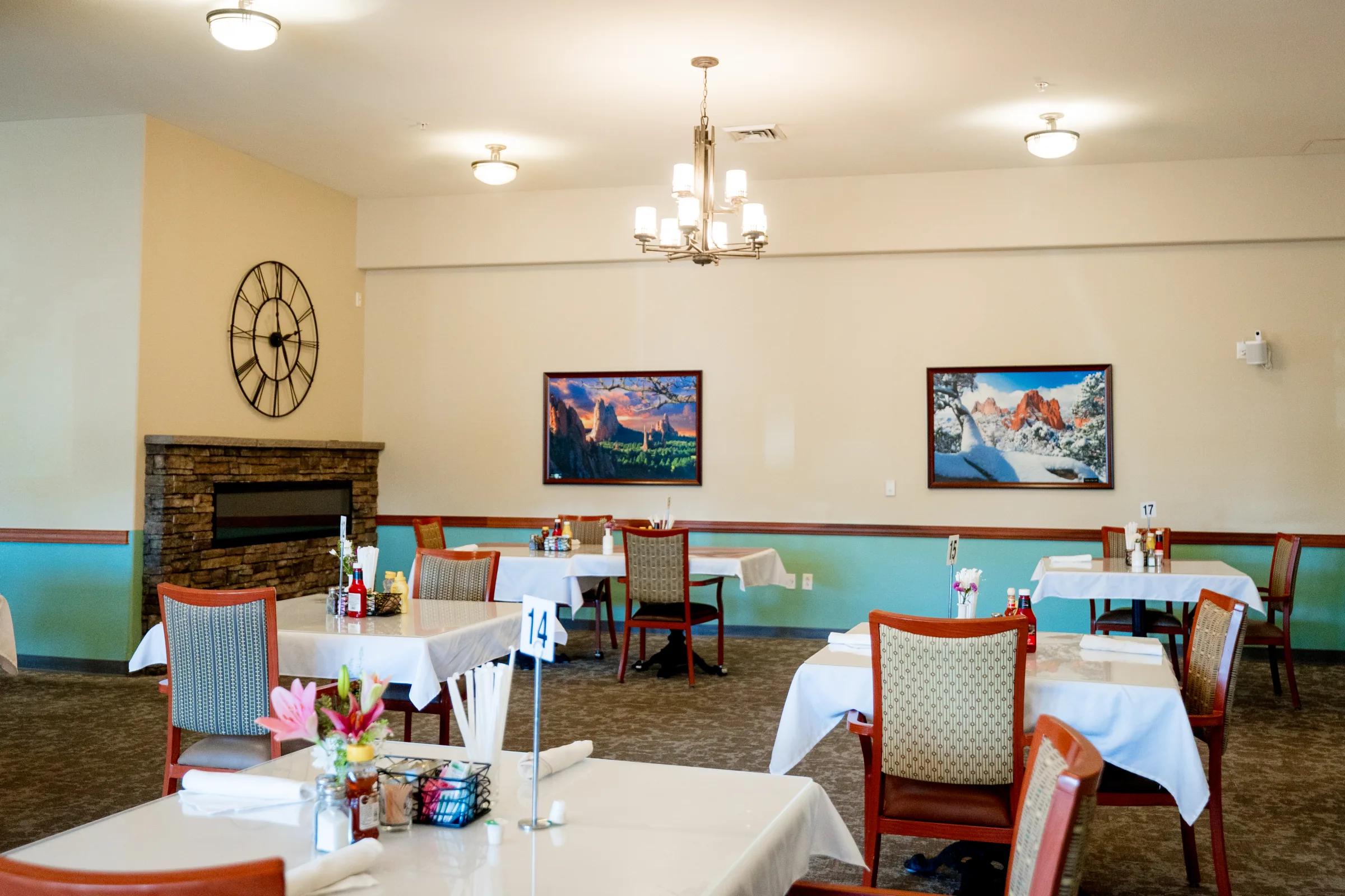 Gardens on Quail dining area with oversized wall clock, faux fireplace, and tables