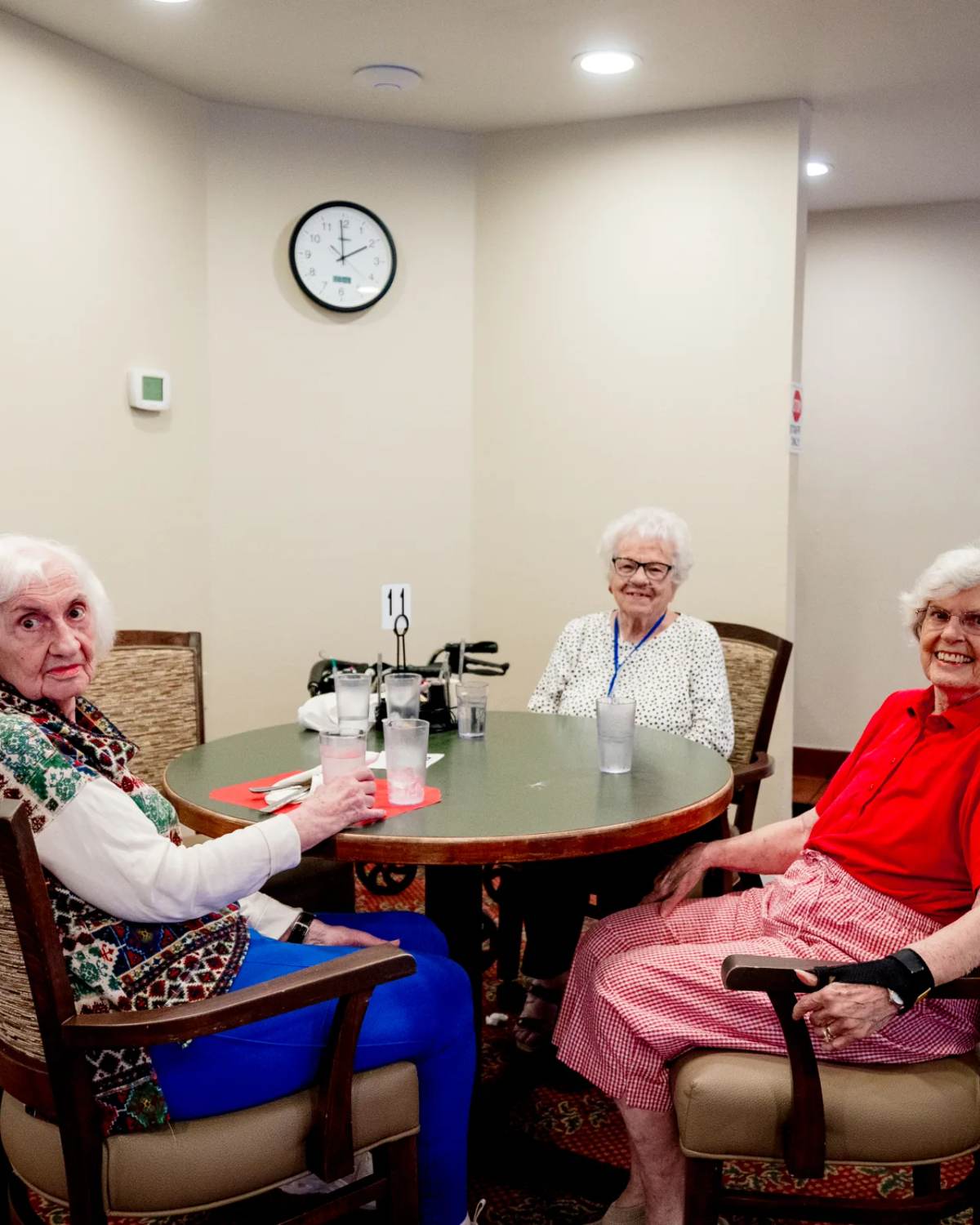 Three Gardens at Columbine residents at a dining table beneath mountain wildflower art