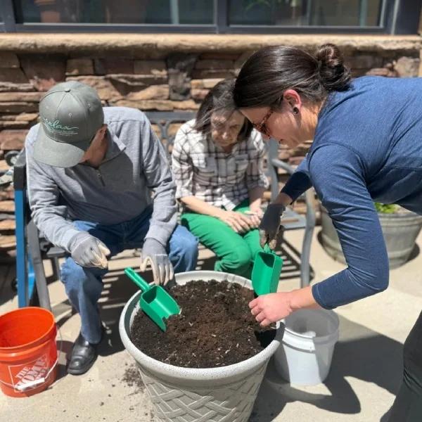 Gardens on Quail resident and team member filling a courtyard planter during a gardening activity