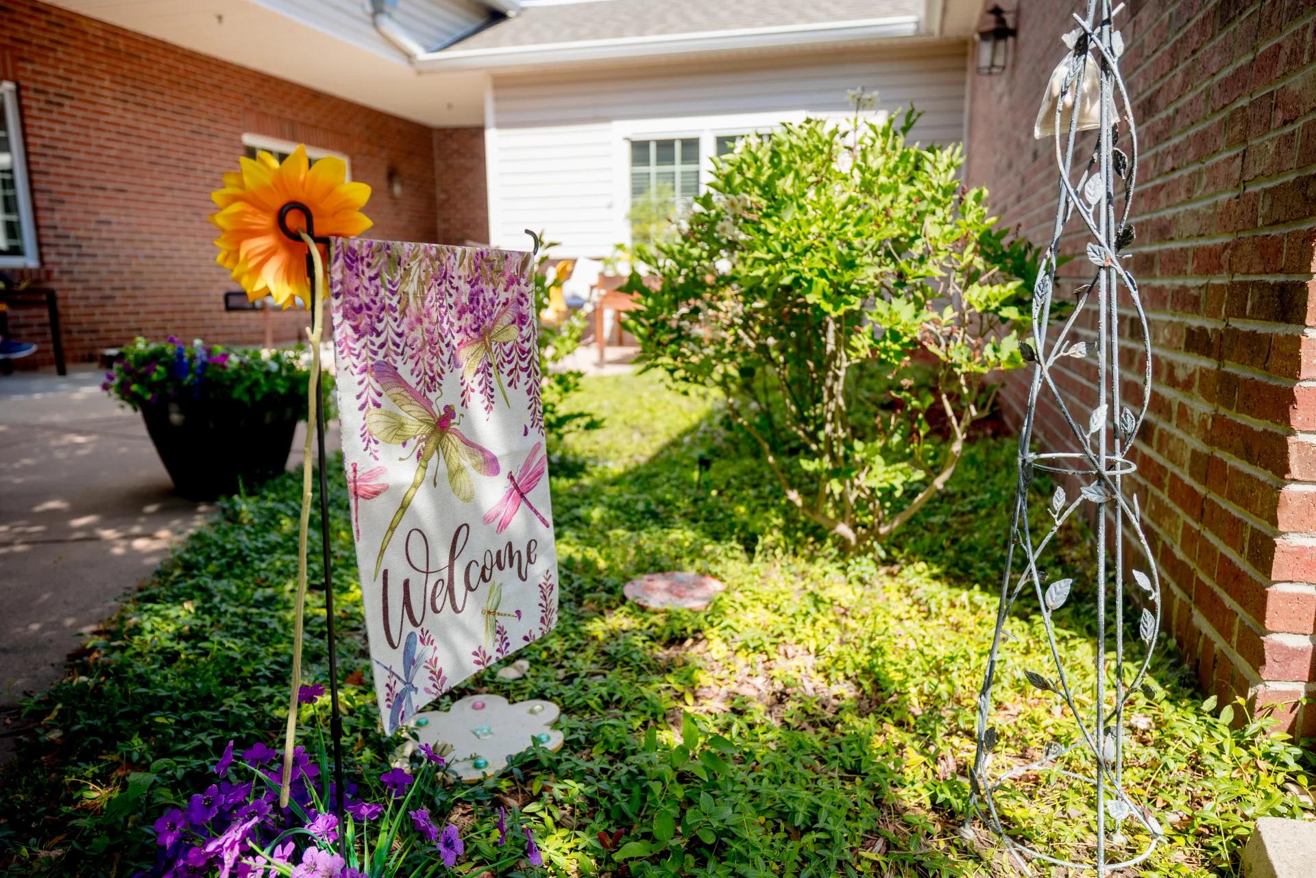 Welcome flag and flowers in the landscaped Bear Creek memory care garden