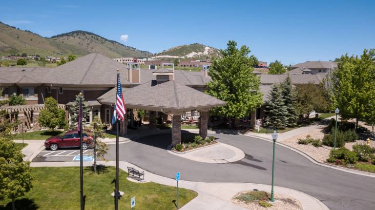 Golden Pond exterior with porte-cochère, American flag, and foothills backdrop