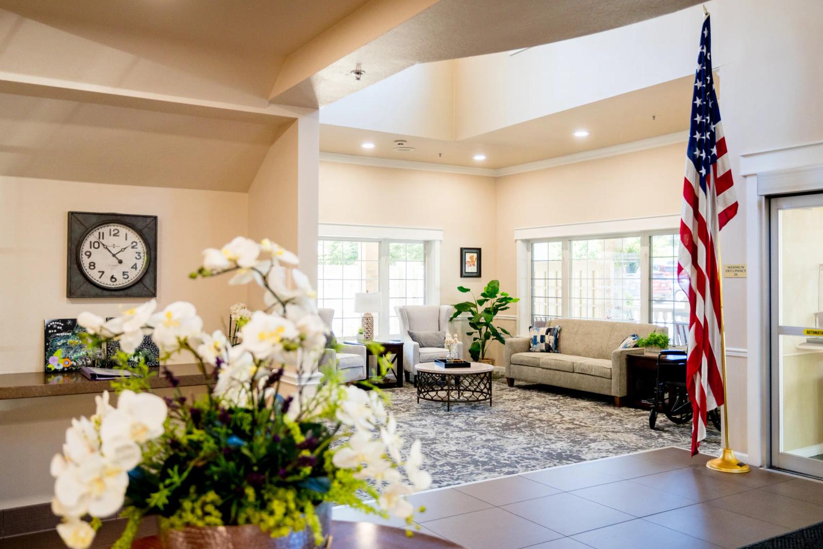 Gardens at Columbine lobby with oversized wall clock, orchids, and seating vignette