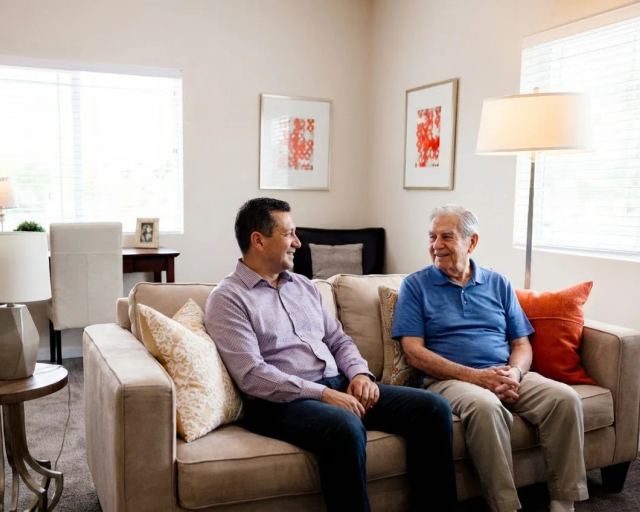 Stonebridge Senior apartment living room with a resident and family member talking on the couch.