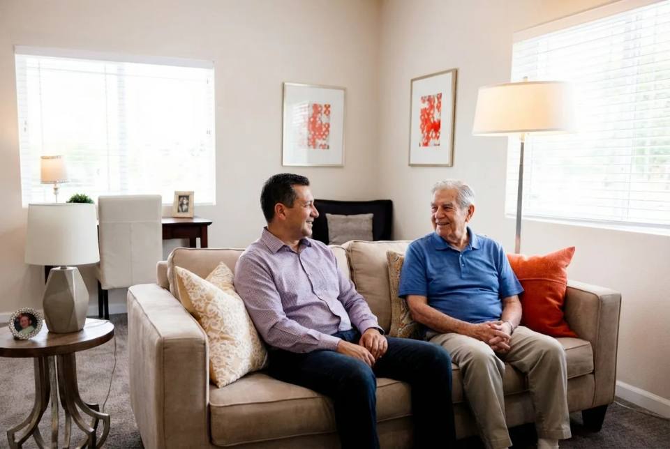 Stonebridge Senior apartment living room with a resident and family member talking on the couch.