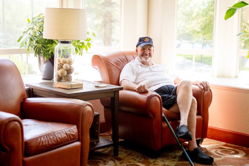 Golden Pond resident with cap relaxing in a leather armchair by the window