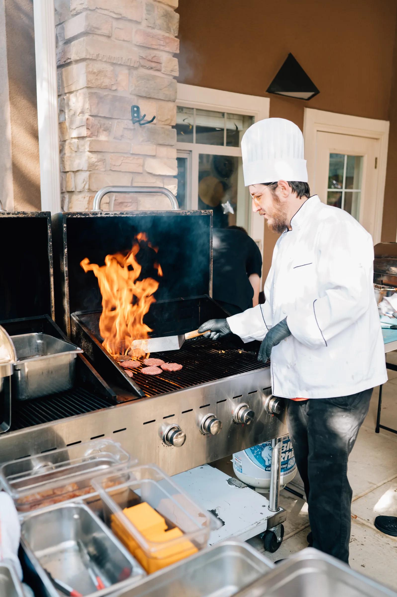 Golden Pond chef flame-grilling burgers at the outdoor grill during a community event