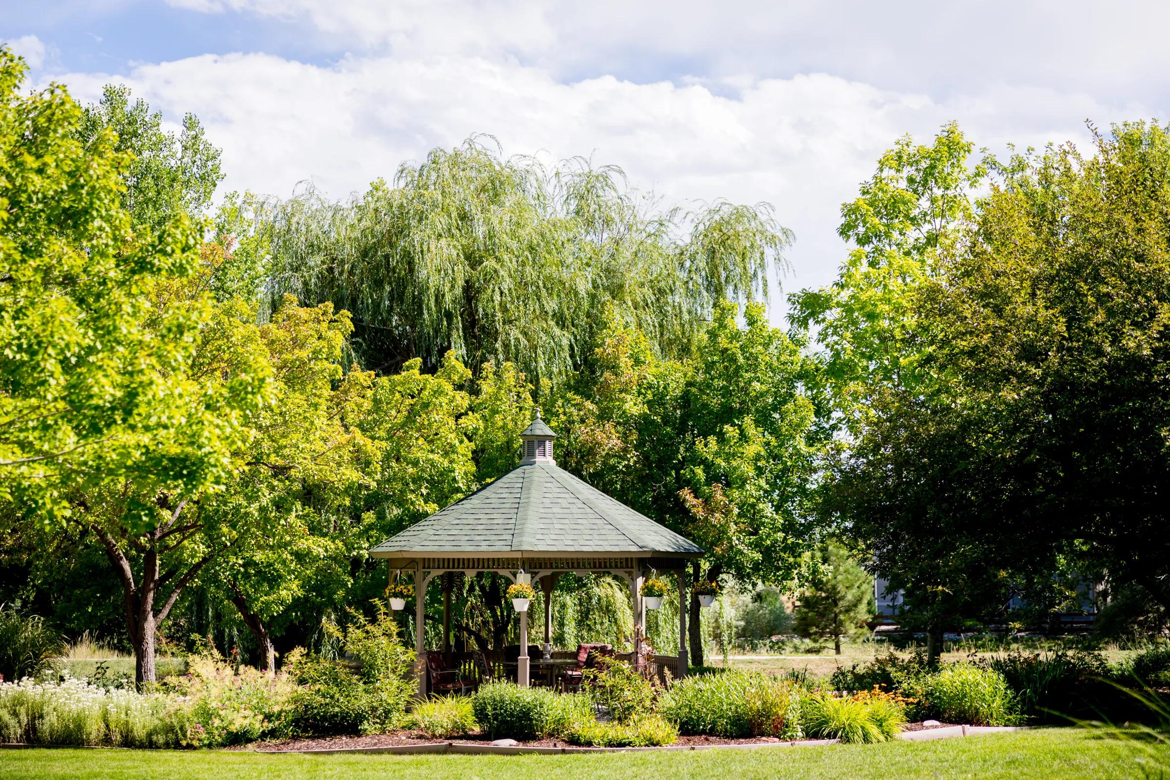 Gardens at Columbine gazebo nestled among willows and summer foliage