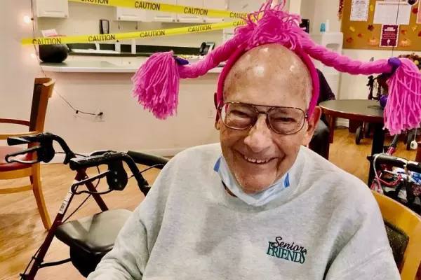Gardens at Columbine resident smiling in a playful pink yarn hat