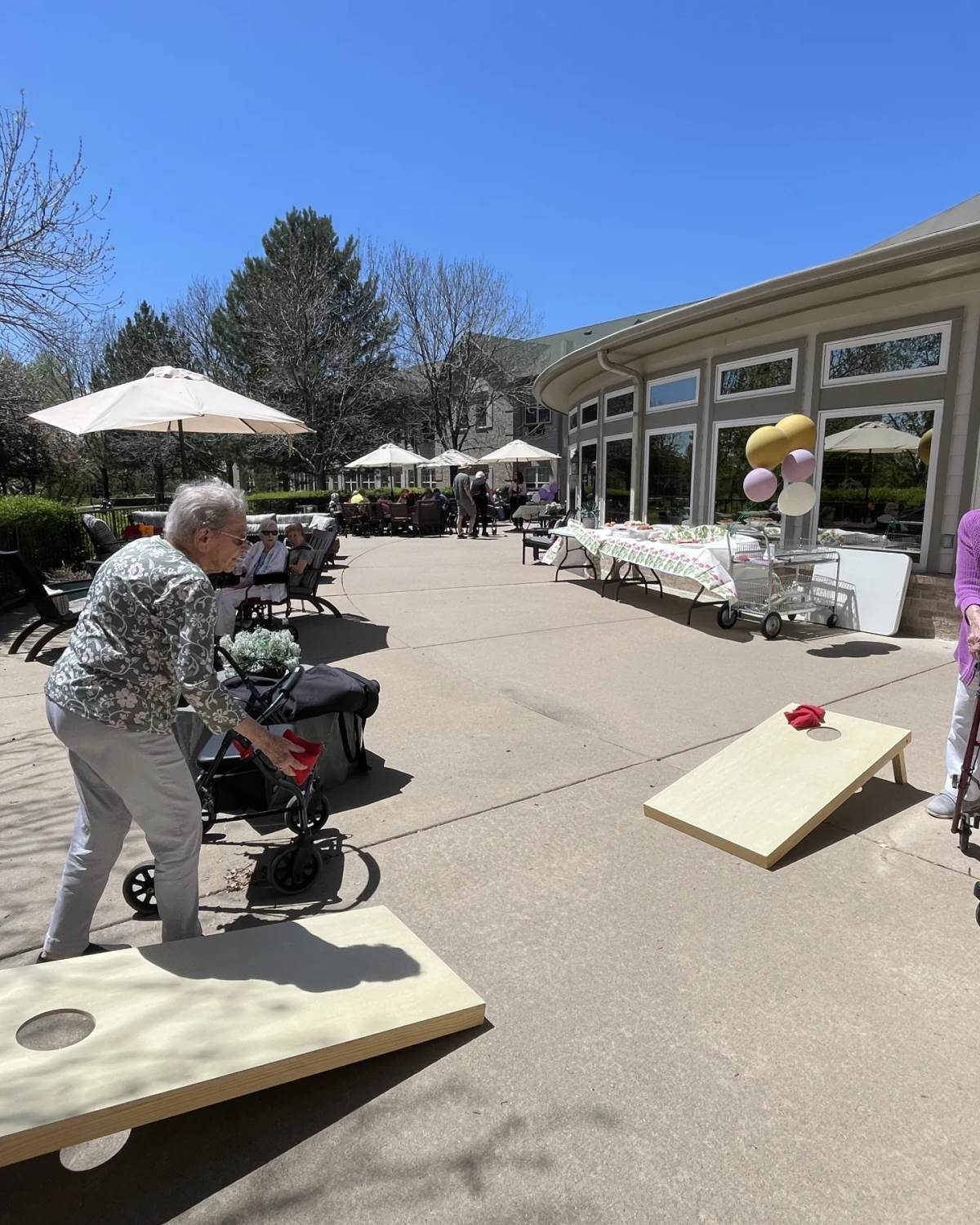 Gardens at Columbine residents playing cornhole on the sunny patio