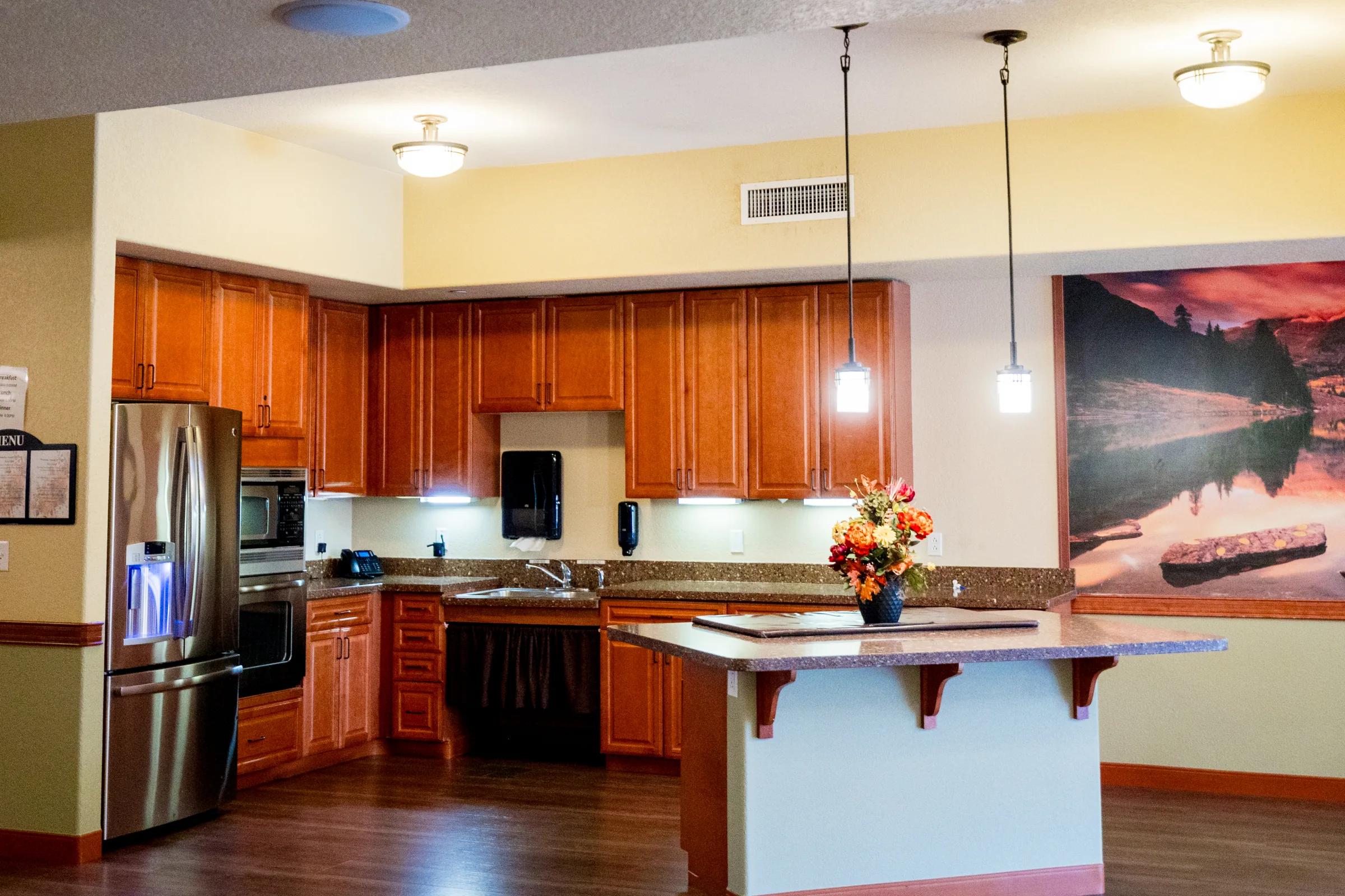 Gardens on Quail demo kitchen with wood cabinetry and large sunset landscape print