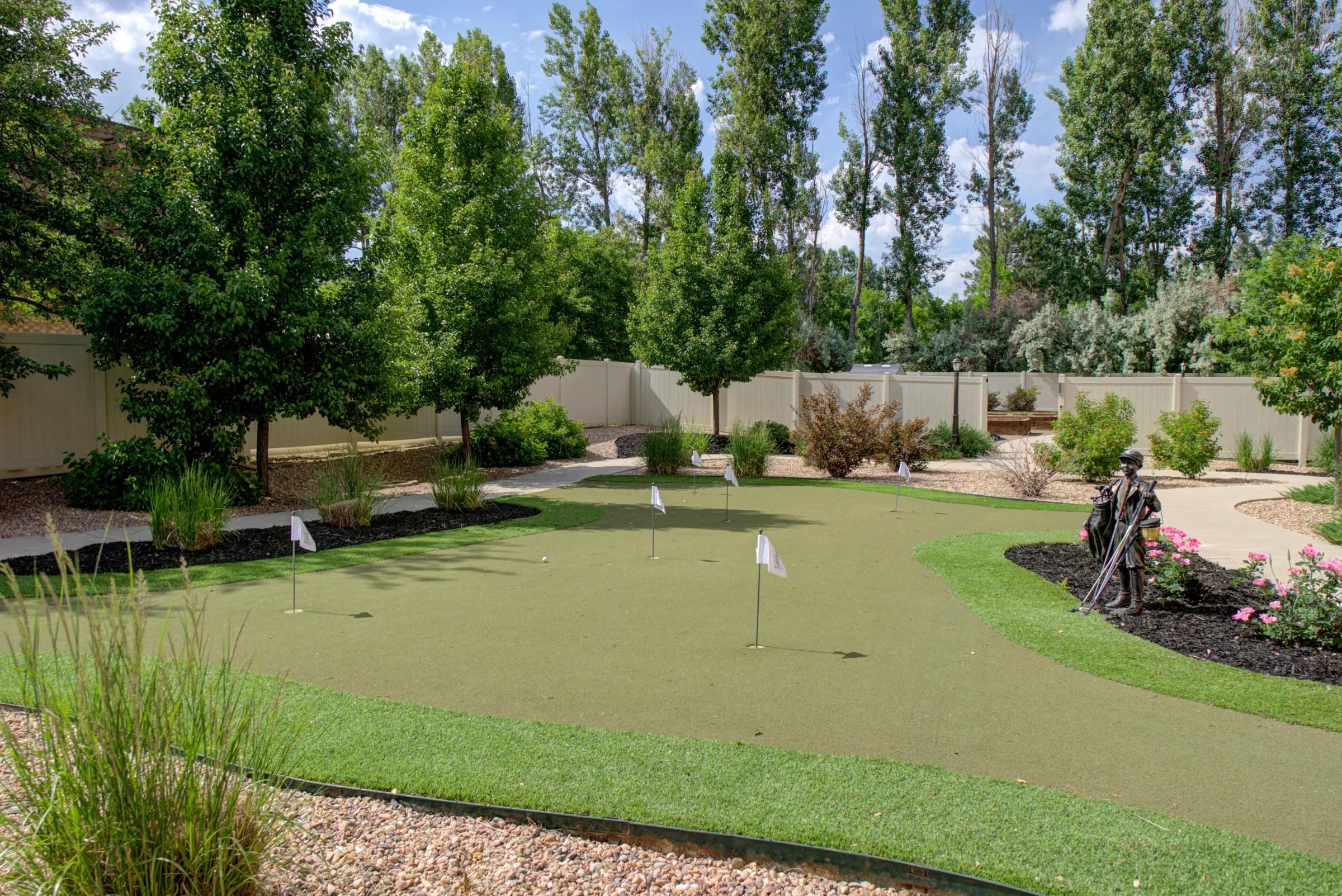 Gardens on Quail outdoor putting green with flags, walking paths, and landscaped trees